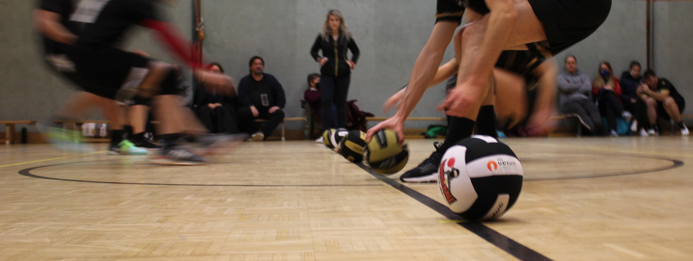 Dodgeball-Spieler greifen beim Spielstart nach den Bällen an der Mittellinie